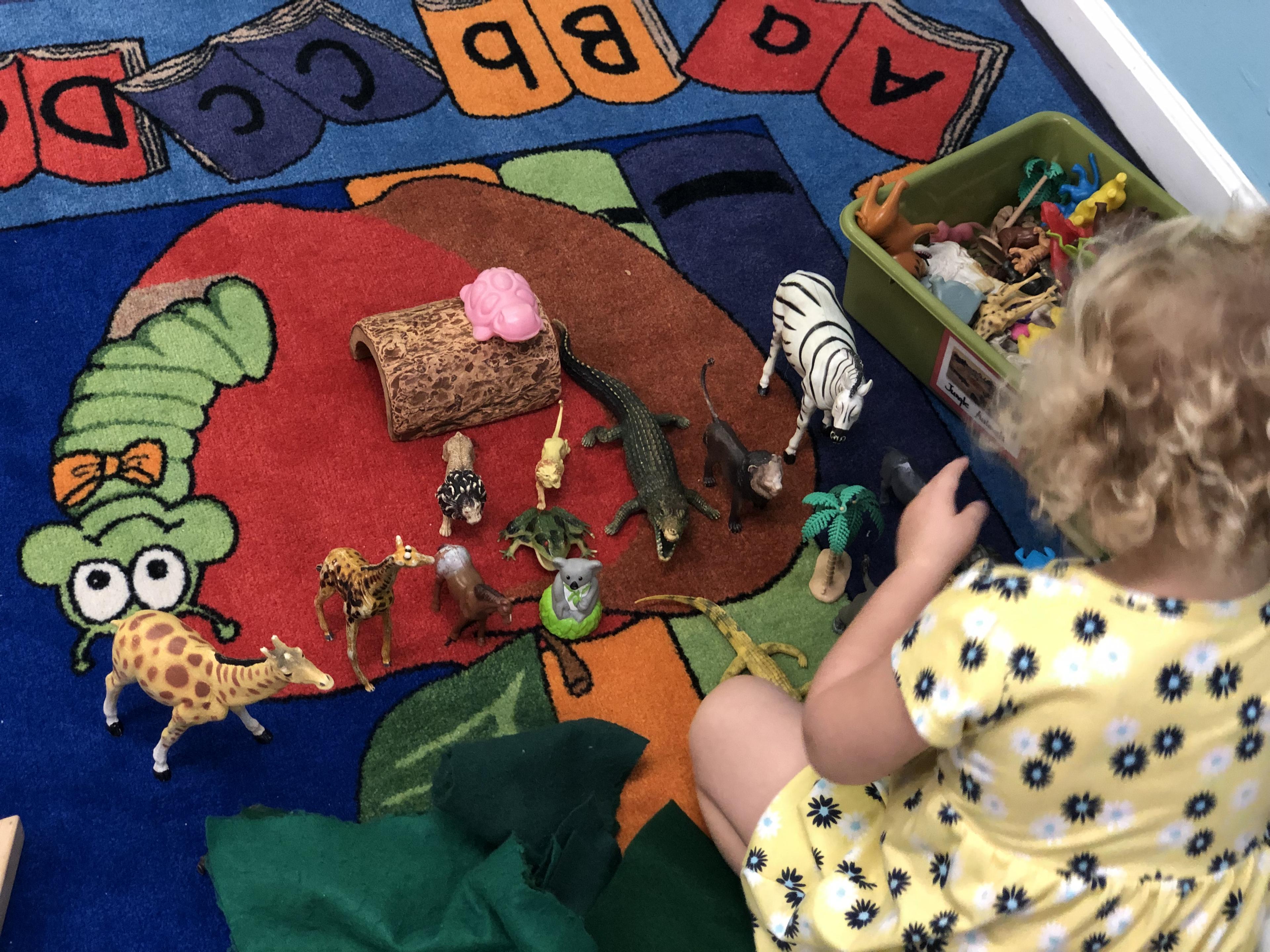 Children playing on a colorful classroom rug at Toad Hall
