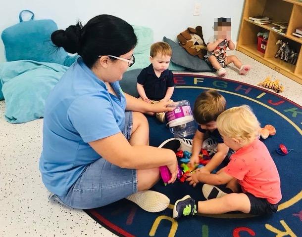 Adult helping children with a classroom activity at Toad Hall